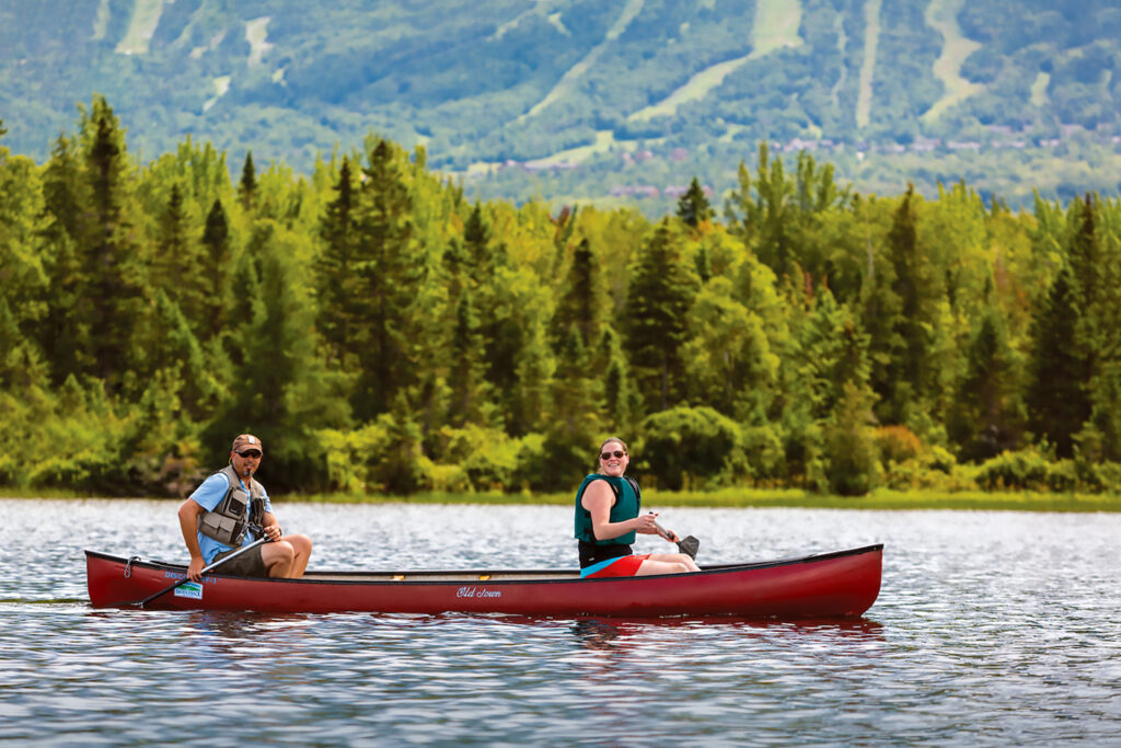 A man and woman canoeing on Saddleback Lake in Dallas Plantation, Maine. High Peaks region near Rangely.